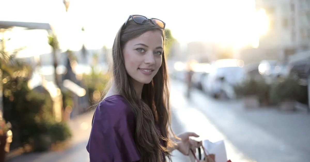 Uma jovem mulher com cabelos longos e olhos claros segura sacolas de compras enquanto sorri.